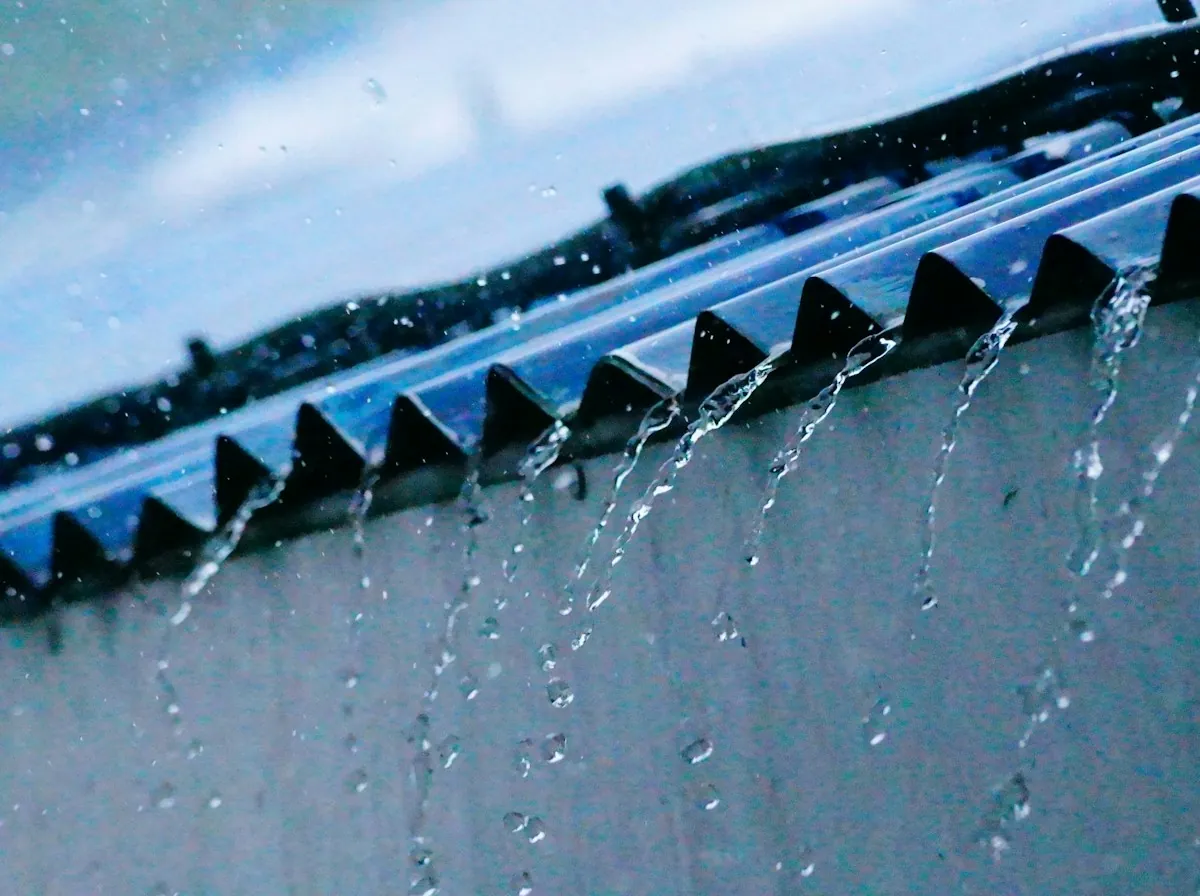 Flat Roof Replacement in Rialto — rain pouring off the edge of a corrugated roof